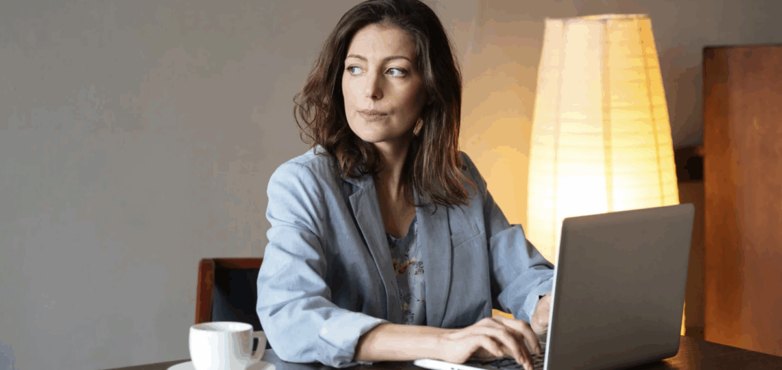 How to write a screenplay. A woman writing in a notebook, looking off to the side in deep thought as she considers her next words.